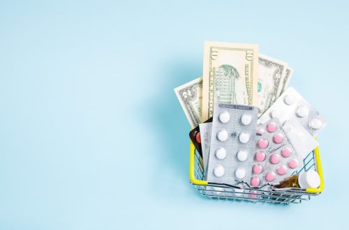 A small shopping basket containing cash and various medication packs against a light blue background.